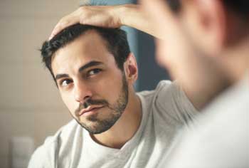 male-checks-hair-line-in-mirror
